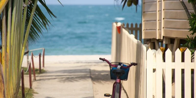 bike parks near white fence in front of the beach