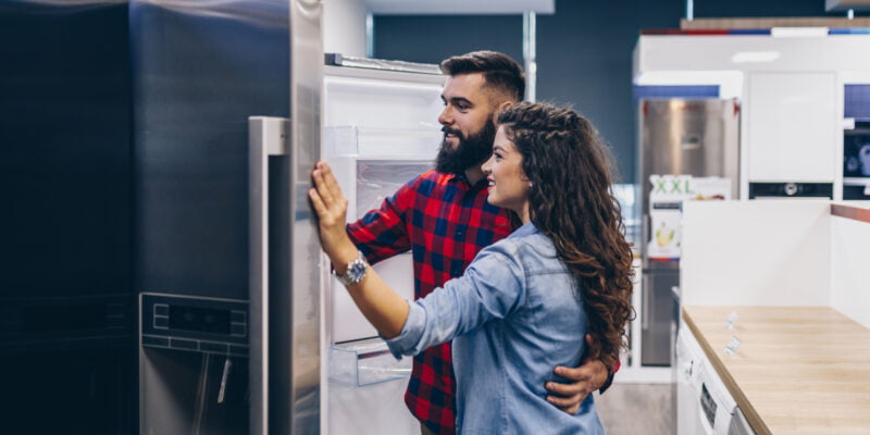 Young couple, satisfied customers choosing fridges in appliances